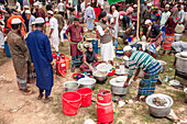 Tongi, Bangladesh - 31 January 2025: View of a bustling outdoor kitchen preparing food with vibrant red buckets and gas cylinders scattered among the cooks.