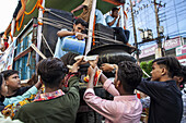 Chattogram, Bangladesh - 20 June 2023: View of devotees offering food from a truck, their faces lit by the soft daylight, creating a scene of shared community and devotion.