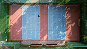 Aerial view of a colorful sports ground with blue and red hues, surrounded by lush greenery and shadowed by trees, Bydgoszcz, Województwo kujawsko-pomorskie, Poland.