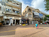 Jerusalem, Israel - 28. Oktober 2019: Blick auf die verwitterten Gebäude der alten Stadt und das pulsierende Straßenleben, wo die strukturierten Fassaden mit den glatten Pflastersteinen und dem hellen Himmel kontrastieren.