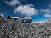 Aerial view of a modern structure nestled amid the rocky terrain under a sky streaked with clouds, Brescia, BS, Italia.