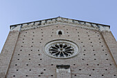 View of the rose window and brick facade ascend towards a pale sky, the church's ancient stones whispering tales of history and faith, Chieti, Abruzzo, Italy.