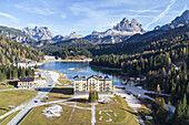Luftaufnahme des großen Hotels, das sich majestätisch am ruhigen See erhebt und in dem sich die hoch aufragenden Gipfel spiegeln, eine Sinfonie der Naturkunst, Misurina, Belluno, Italien.