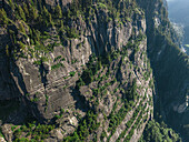 Luftaufnahme eines zerklüfteten, strukturierten Berghangs mit grünen Baumgruppen, der die raue Schönheit der Natur zeigt, Sethan, Himachal Pradesh, Indien.