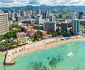 Luftaufnahme des kultigen, rosafarbenen Royal Hawaiian Hotels am Sandstrand von Waikiki vor dem Hintergrund der hoch aufragenden Gebäude, Waikiki, Honolulu, Hawaii, Vereinigte Staaten.