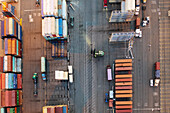 Oakland, United States - 12 May 2020: Aerial view of a vibrant port where colorful shipping containers stack high, casting long shadows and creating a geometric tapestry of global trade.