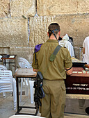 Jerusalem, Israel - 03 November 2019: View of a soldier stands in solemn reflection before the Western Wall, its ancient stones weathered by time, a poignant scene of faith and duty.