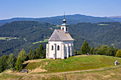Aerial view of the Wolfgangikirche, a beacon of white stone against the verdant hills, stands proudly under the vast blue sky, Deutschlandsberg, Styria, Austria.