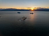 Aerial view of the Bourtzi castle standing proudly amidst the tranquil waters, ships sailing into the horizon under the golden sunset, Nafplion, Argolis, Greece.