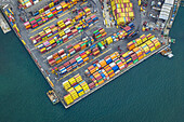 Aerial view of a vibrant tapestry of stacked shipping containers, a symphony of colors against the deep blue sea, Port of La Spezia, Liguria, Italy.