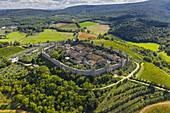 Aerial view of the ancient walled city of Monteriggioni, a medieval fortress amidst rolling hills and verdant fields, Siena, Tuscany, Italy.