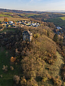 Aerial view of the tower standing sentinel amidst the autumnal hues of the forest, with a village nestled in the valley beyond, Dolná Miciná, Banskobystrický kraj, Slovakia.