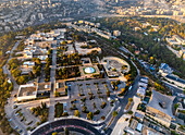 Aerial view of The Israel Museum's buildings and grounds bask under a golden light, contrasting with the cool shadows and the distant city, Jerusalem, Israel.