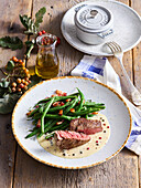 Beef steak with green pepper sauce and bacon and beans