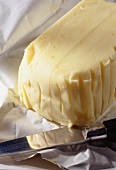 Ein ganzes Stück Butter mit Messer auf Butterpapier