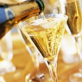 Full glass of champagne with pouring champagne bottle