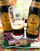 Zwei Flaschen Guinness mit einem Glas und Dartpfeil