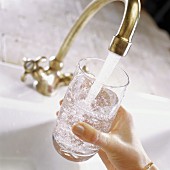 Glass of water under running tap