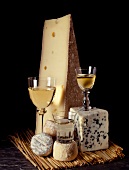 Käsestillleben mit Ziegenkäse, Comté, Roquefort und drei Gläsern Weißwein