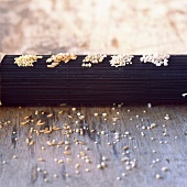 Getreidekörner auf schwarzer Bambusmatte: Hirse, Dinkel, Buchweizen, Quinoa, Perlgraupen