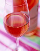 Ein Glas Roséwein, Flasche im Hintergrund