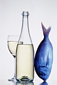 Weissweinglas und Flasche neben einem Fisch