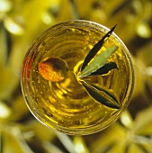 Glas mit Olivenöl und frischer Olive (Aufsicht)