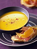 Creamed pumpkin soup with mountain ham on bread