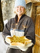 Junge Frau hält eine vegane Kohl-Tarte mit Curry und Mohnsamen