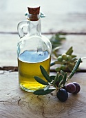 Flasche mit Olivenöl, daneben Olivenzweig