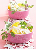 Pfirsichsalat mit Zwiebelringen und Mandelblättchen in rosa Schälchen