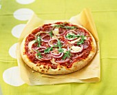Pizza mit Mozzarella, scharfer Salami, Zwiebeln und Rucola