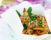 Sliced chicken breasts with spring vegetables cooked in wax paper