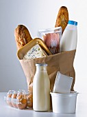 Einkaufstüte mit verschiedenen Lebensmitteln: Baguette, Milch, Käse, Speck und Eier
