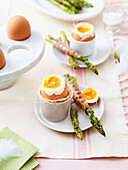 Soft-boiled eggs with green asparagus wrapped in bacon