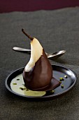 Pear coated in chocolate, custard and pistachios