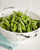 Peas in their pods in a colander