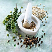 Black,green and white peppercorns and a mortar