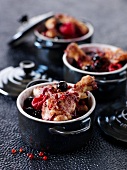 Small casserole dishes of young cockerel with summer fruit