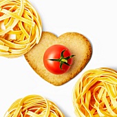 Heart-shaped biscuit witha cherry tomato and tagliatelle nests
