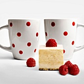 Piece of raspberry cake and two cups