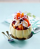 A melon filled with berries and apricots and meringue