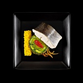 Gedämpfter Zander mit Zucchinigemüse und Safranreis auf schwarzem Teller