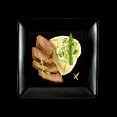 Veal rump,pureed white and green asparagus and creamy lemon sauce on a black background