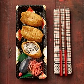 Inari Sushi auf japanischem Geschirr mit Stäbchen