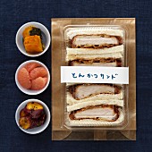 Sandwich mit paniertem Schweinefleisch und verschiedene Beilagen