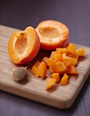 Halbierte und gewürfelte Aprikosen auf Holzbrett