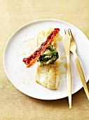 Pan-fried pike-perch with parmesan, spinach and mashed potato ball and a strip of fried bacon