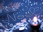 Das Wort Noel, mit einer Schnur geschrieben, als weihnachtliche Tischdekoration