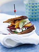 Honigbrot-Sandwich mit geräucherter Entenbrust, Kiwi, getrockneten Aprikosen und Ziegenfrischkäse mit Schnittlauch